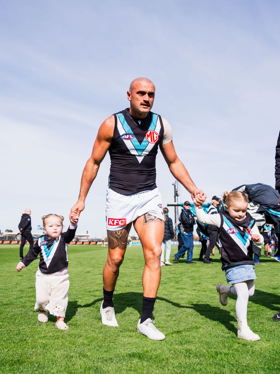 Sam Powell-Pepper walking off the ground holding two of his daughters by the hand.