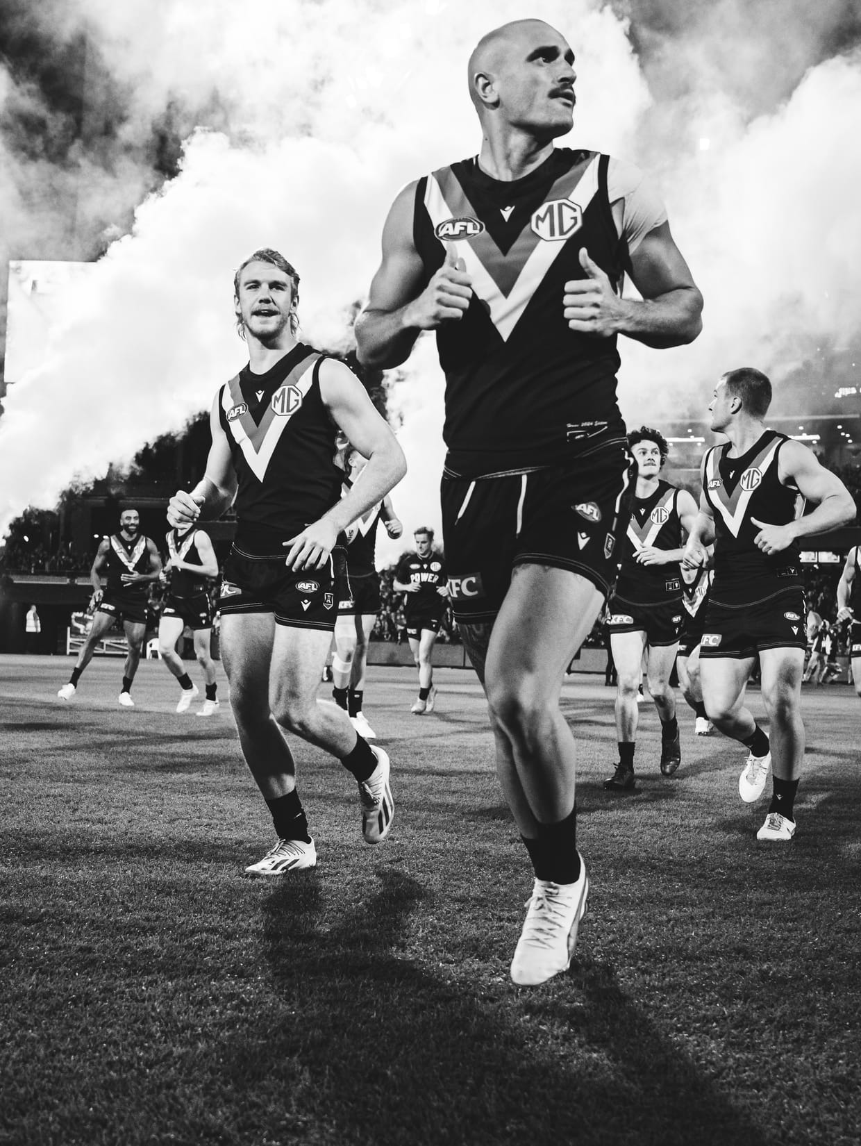 Sam Powell-Pepper running onto the ground through smoke with his teammates.