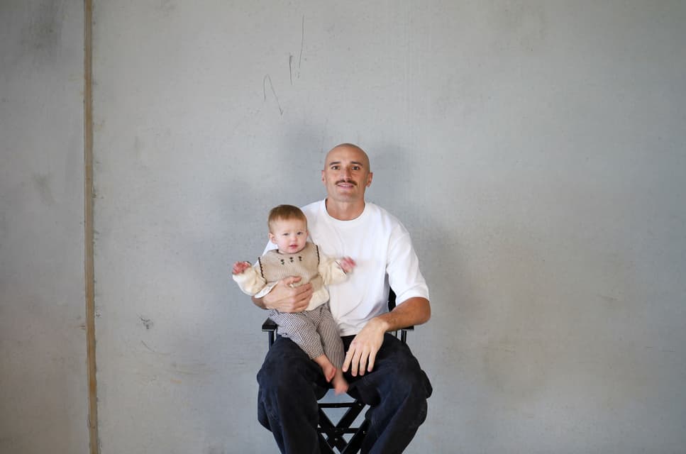 Sam Powell-Pepper holding his youngest daughter against a concrete wall.