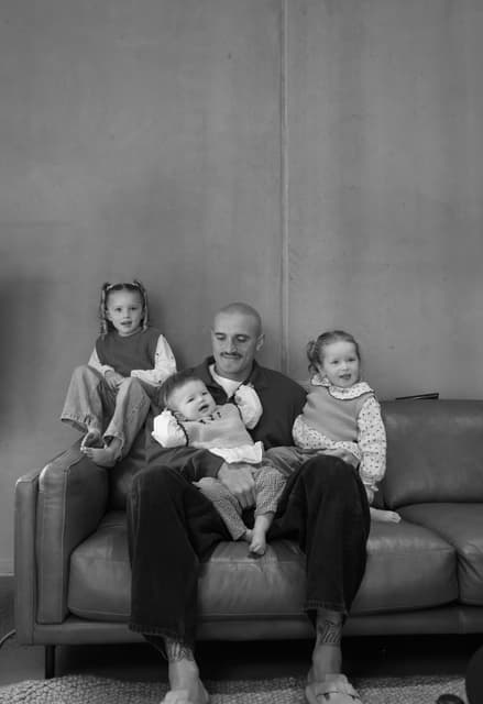 Sam Powell-Pepper and his three daughters on the couch, in black and white.