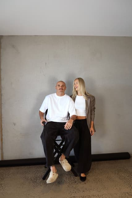 Sam Powell-Pepper with his wife Brya against a concrete wall.