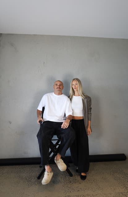 Sam Powell-Pepper and his wife Brya, photographed against concrete.